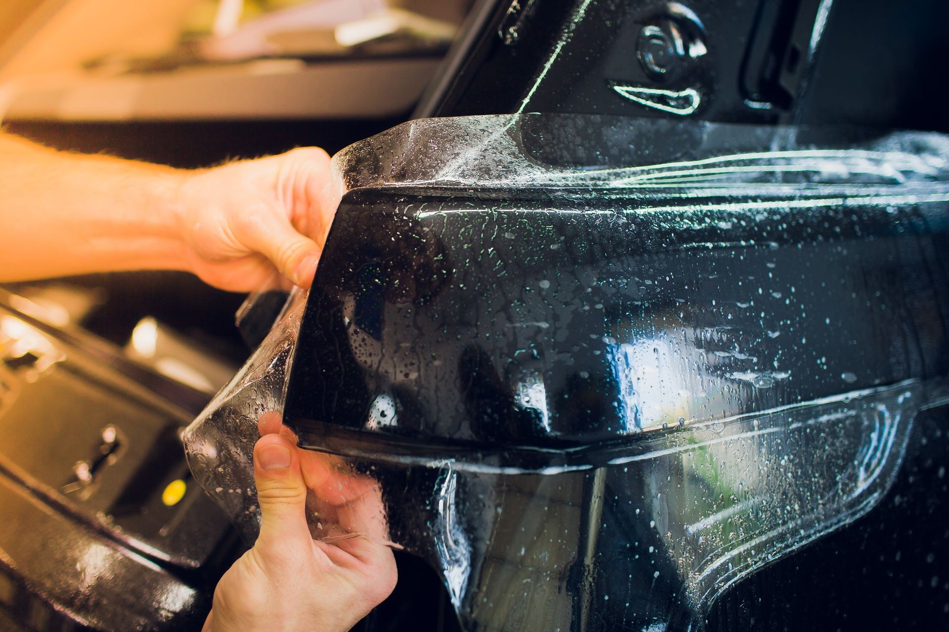 Worker hands installs car paint protection film wrap.